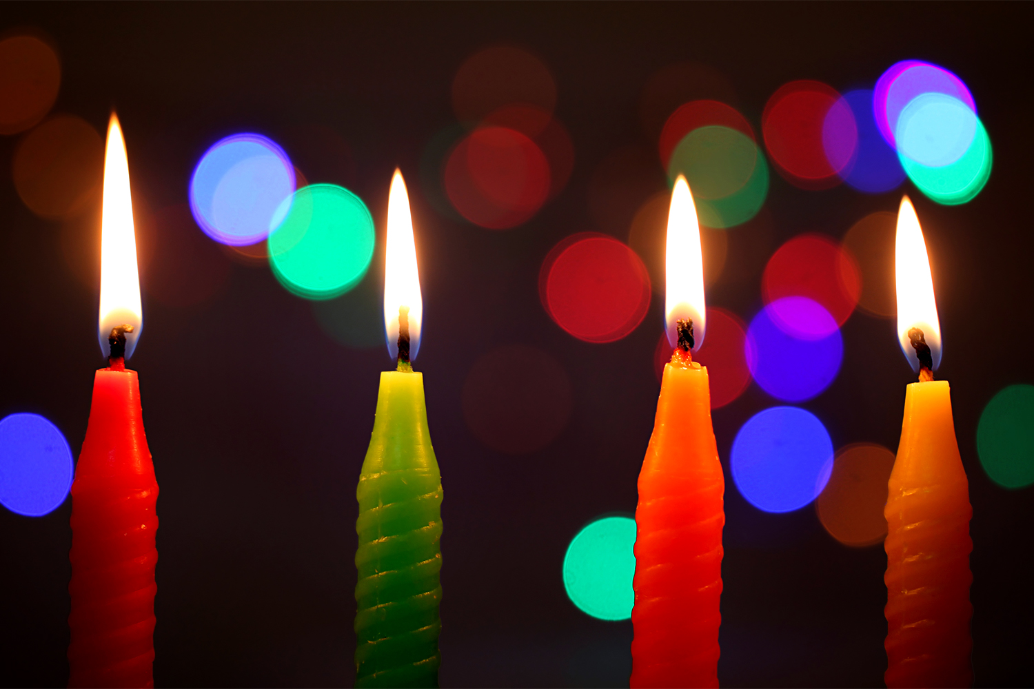 candles in the dark in front of strings of twinkling lights