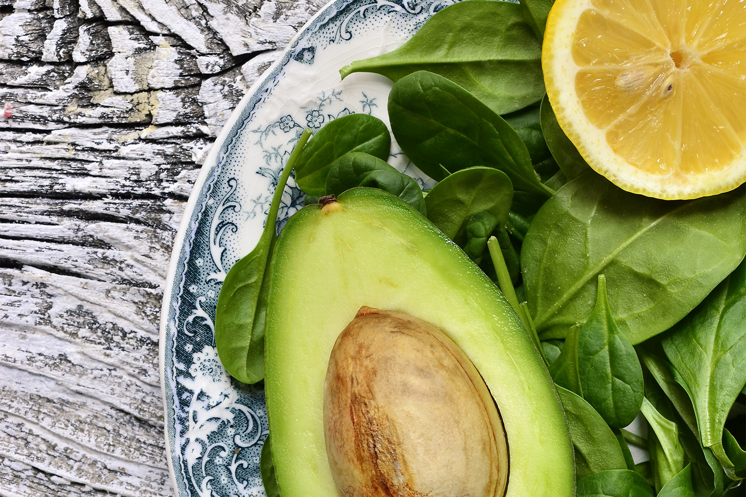 Assortment of spinach, lemon, and avocado on a plate