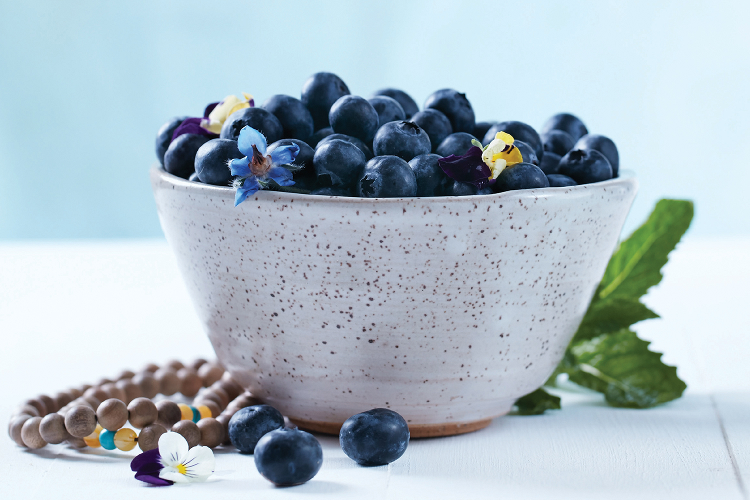A bowl of blueberries and some Buddhist prayer beads