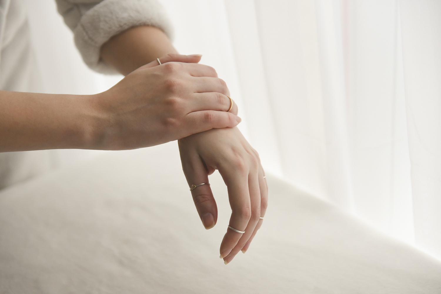 a woman in a sweater rubbing ointment on her hands