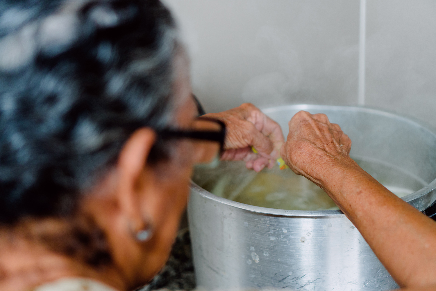 a grandmother putting cut-up vegetables into a boiling pot