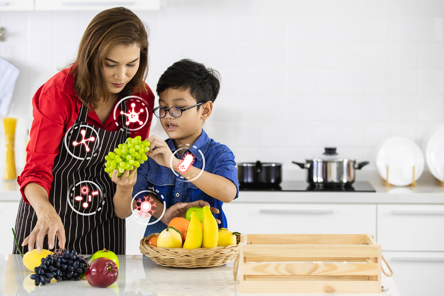 A mother and son i n the kitchen selecting fruits with icons of probiotic bacteria.