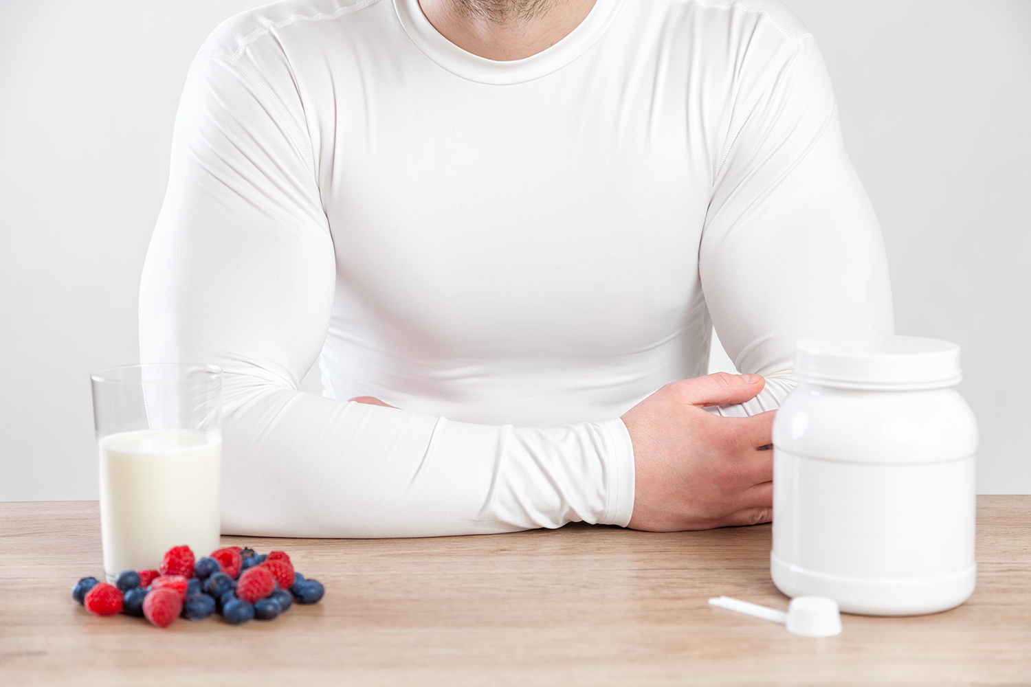 A muscular man at a table with fruits and supplements