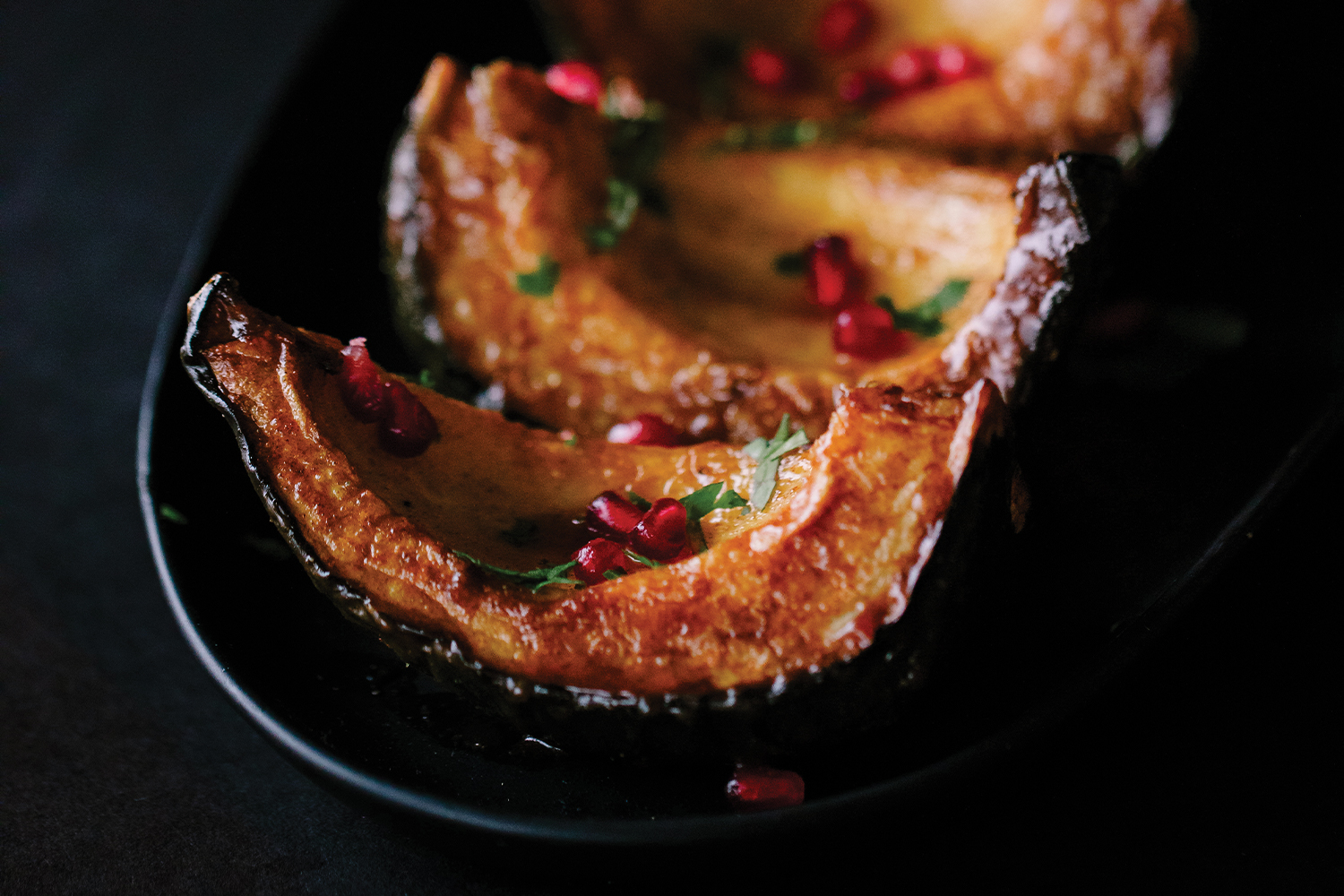 Spice-Drizzled Acorn Squash served on a black platter with a black background.