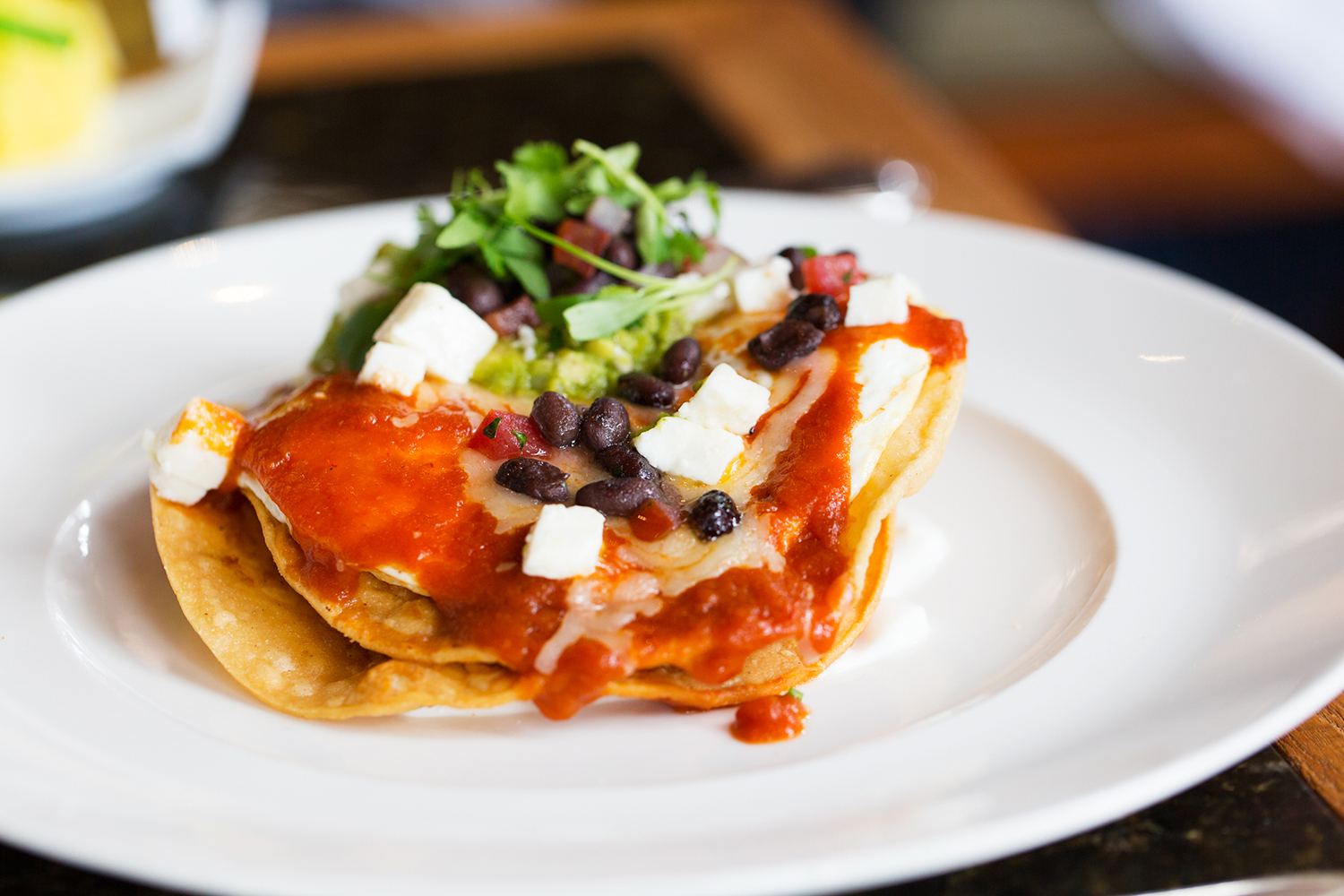 a plate of poached eggs and beans on a corn tortilla
