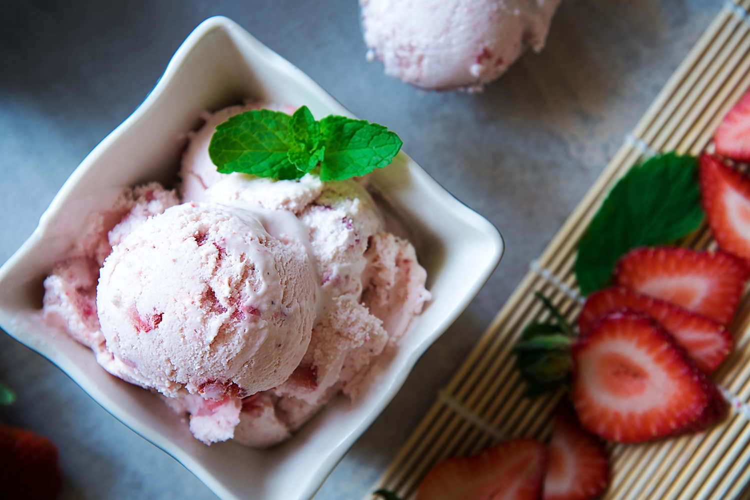 Homemade strawberry ice cream with fresh strawberries in a bowl.