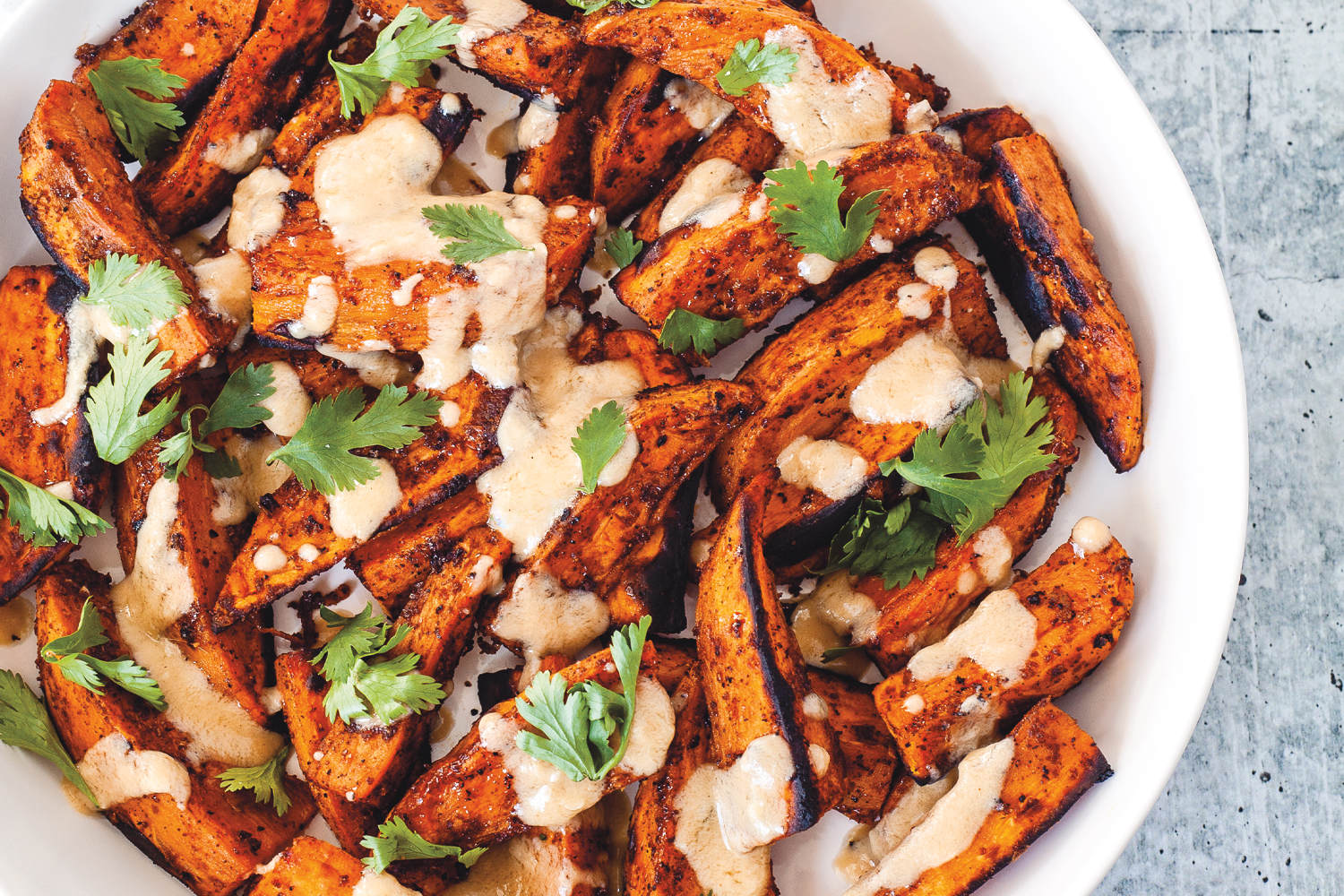 sweet potatoes plated with tahini and cilantro