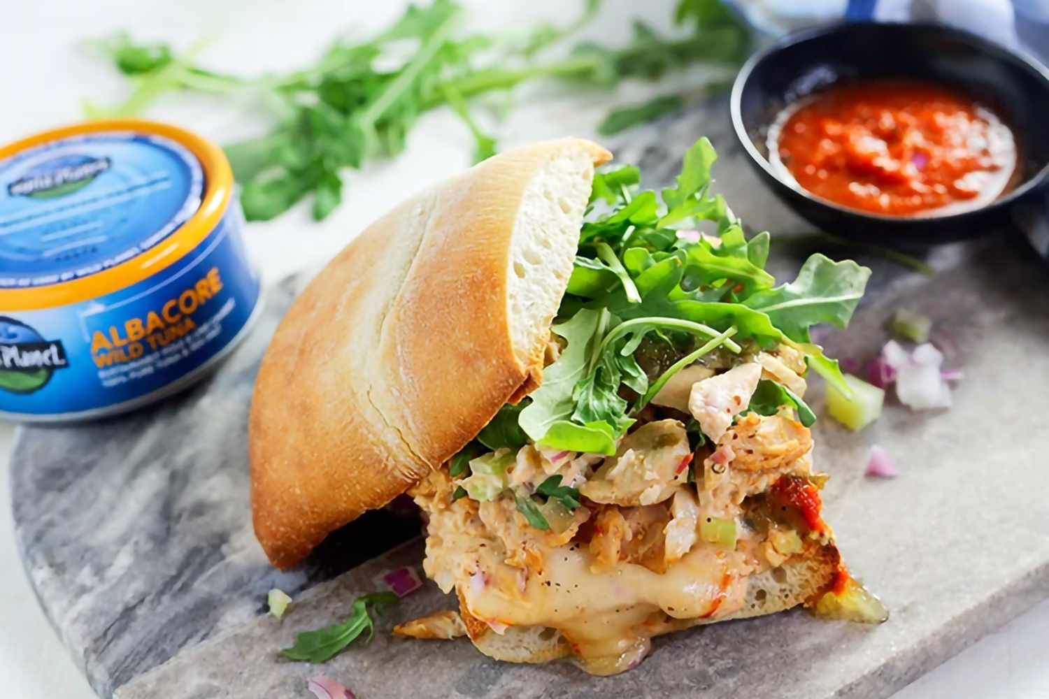 a tuna sandwich with cheese and spicy sauce