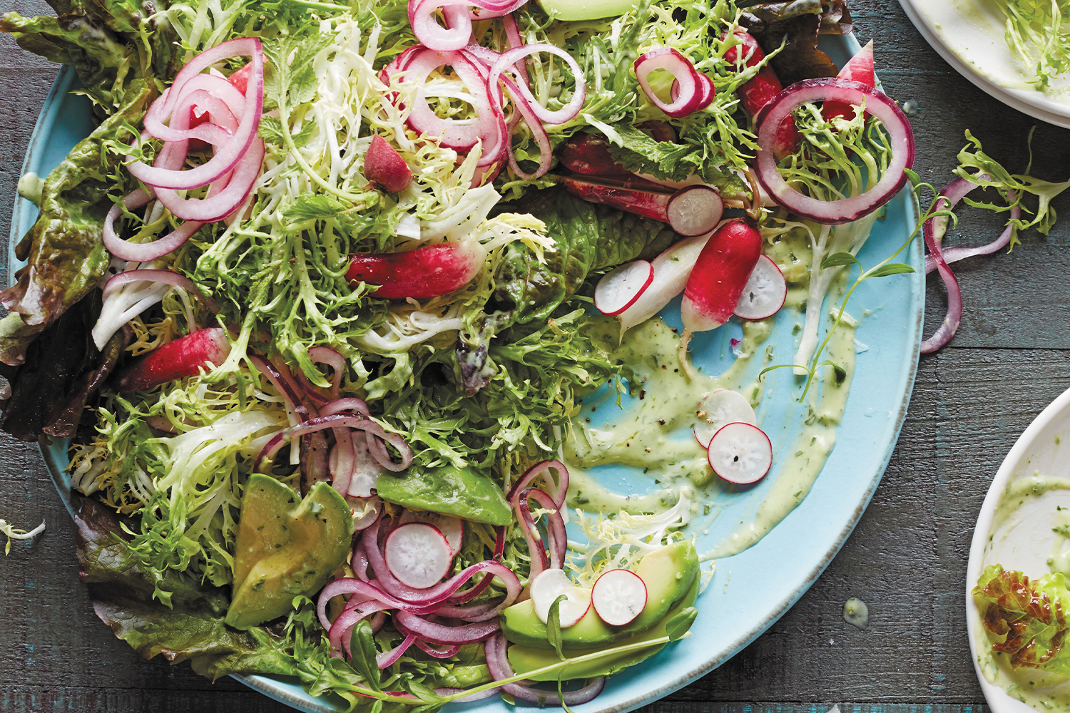 Frisee salad on a blue plate with a gray wood background.