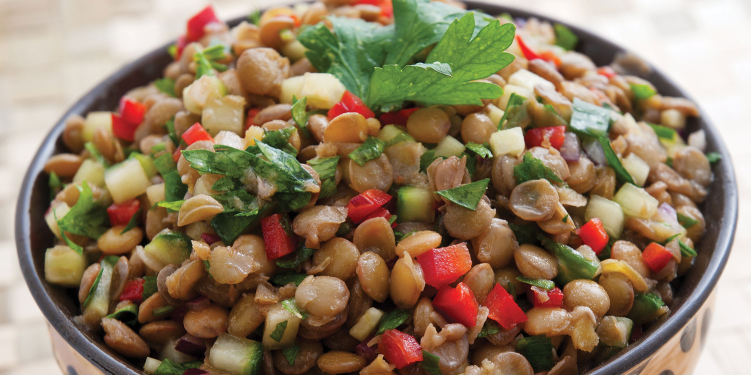 a bowl of lentils and veggies with garnish