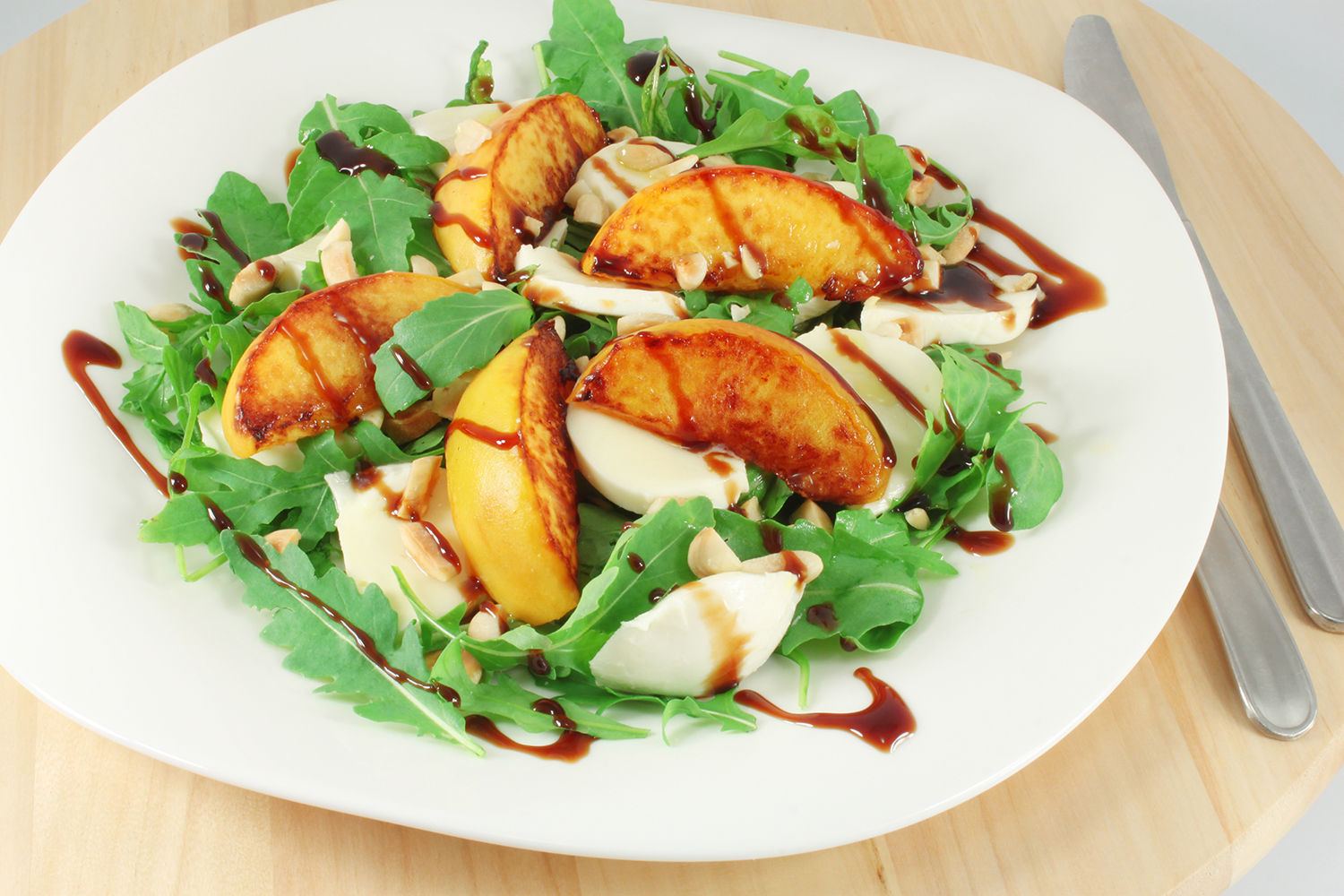 A plate of arugula with peaches and mozzarella