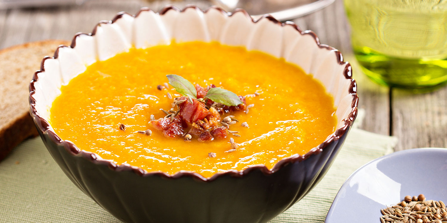 A bowl of carrot ginger soup, garnished