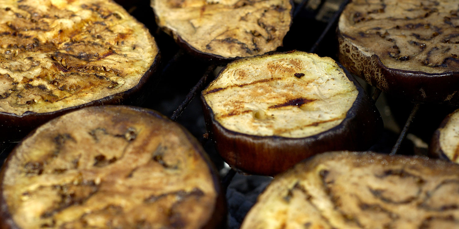 Sliced eggplant roasting on grill
