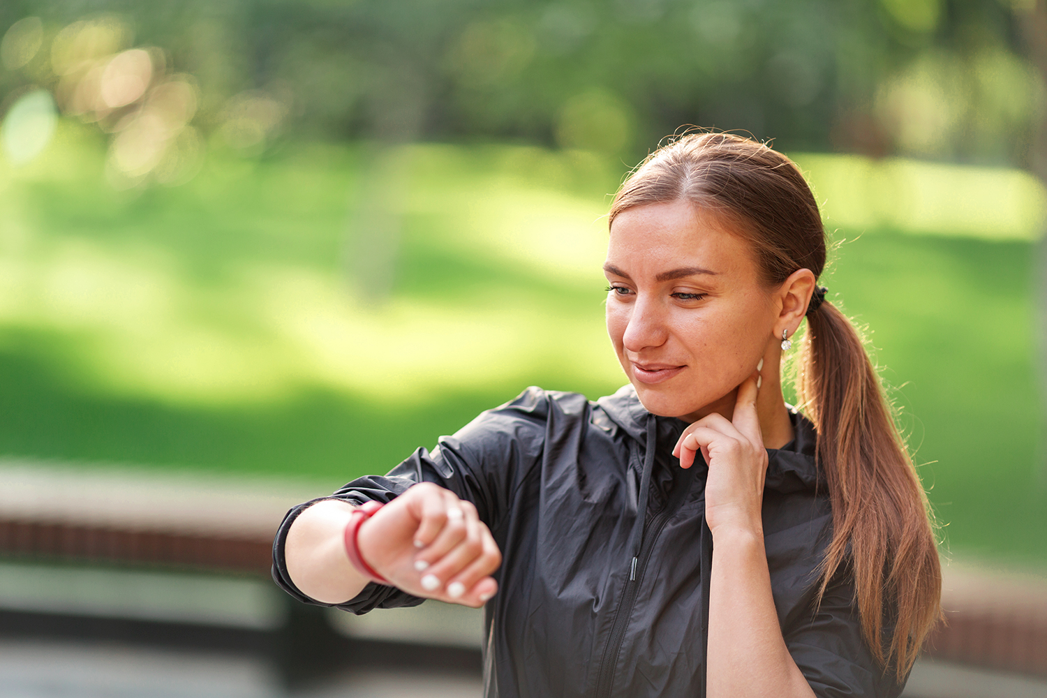 a young woman checking her pulse in the park