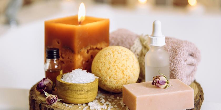 natural body care ingredients and candles next to a warm bath