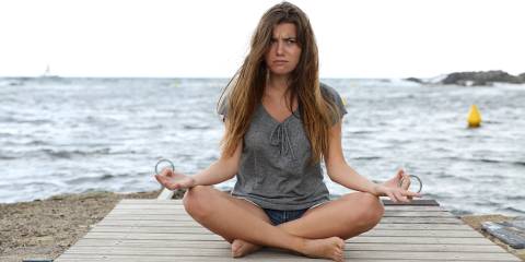a frustrated woman trying to do half-lotus pose