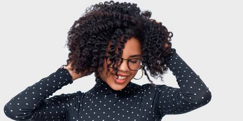 African American female smiling broadly with her hands in her beautiful, healthy hair.