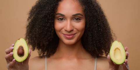 a woman with beautiful skin holding avocados