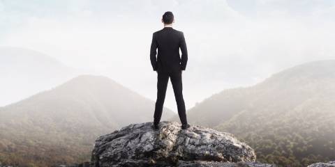 Man in suit stands looking out at the world