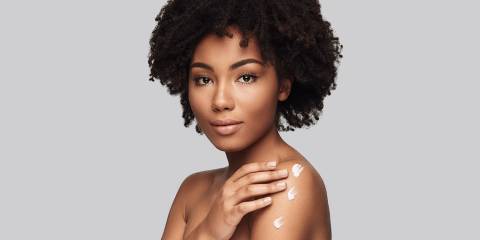 Woman rubbing lotion on her skin 