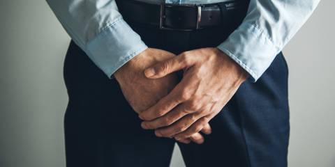 a man patiently holding his crotch