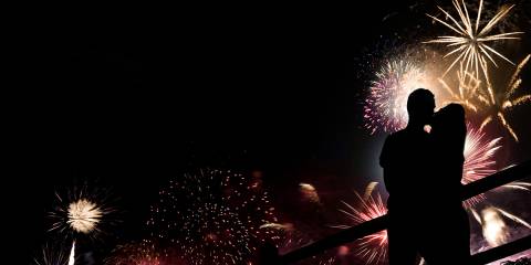 lovers kissing in front of a sky full of fireworks