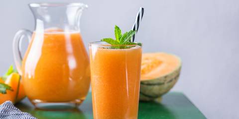 a glass of melon smoothie and slices of cantaloupe