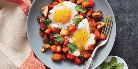 A bowl of vegetable hash with eggs roasted on top