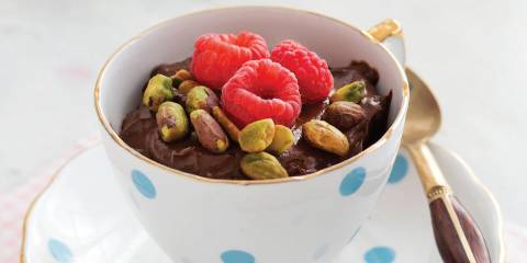 A dish of chocolate pudding with raspberries and pistachios