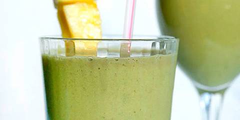 a glass of fruit smoothie with matcha garnished with pineapple