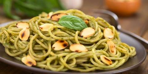 Dish of whole grain pasta, pesto and slivered almonds.