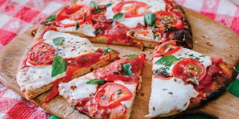 Margherita Flatbread Pizza on a wooden pizza board, cut and ready to serve.