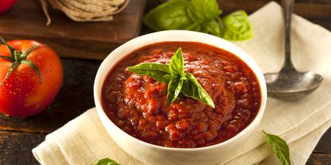 a bowl of marinara with a basil garnish