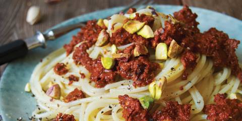 Spaghetti with Sun-Dried Tomato and Pistachio Pesto on a blue plate.