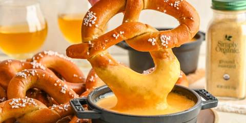 a soft pretzel being dipped in beer cheese
