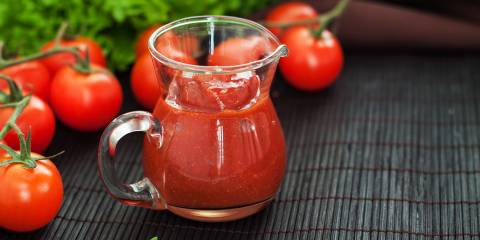 a pitcher of fresh ketchup surrounded by tomatoes