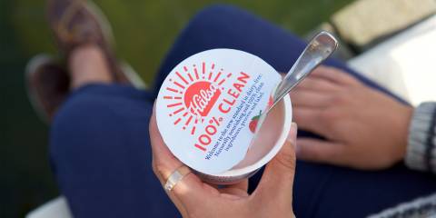 a woman eating yogurt with that claims to be 100% clean