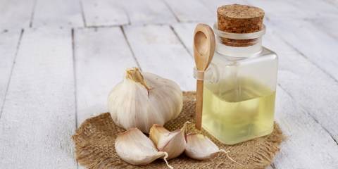 whole and chopped garlic next to a bottle of extract