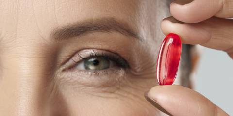 a woman holding a capsule of krill oil