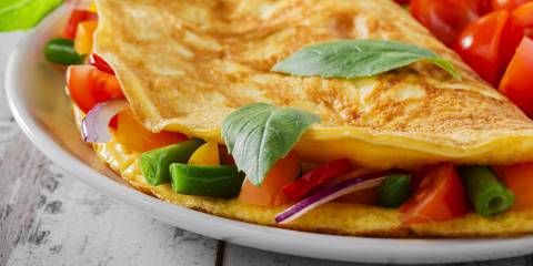 a perfectly-cooked omelet with veggies and chopped cherry tomatoes